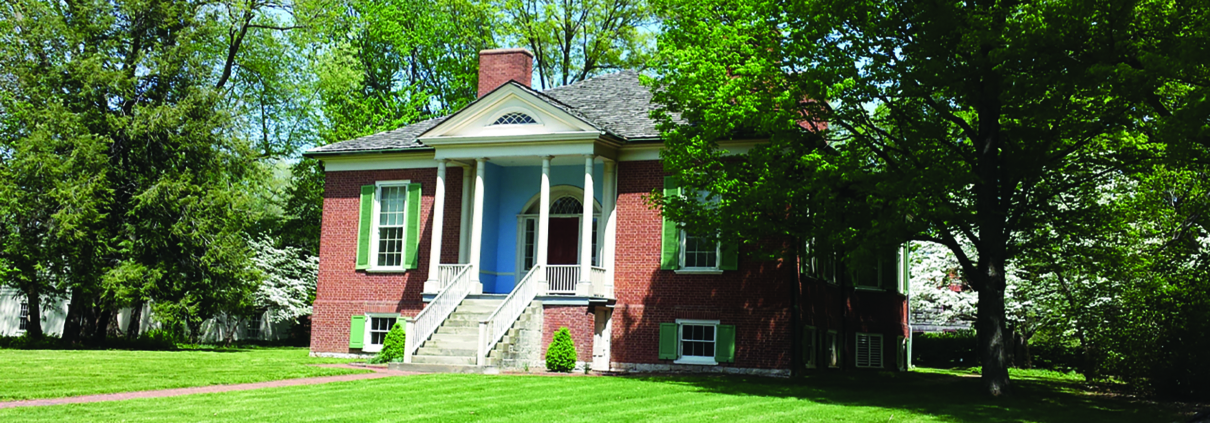 An image of a red brick home nestled among the trees.