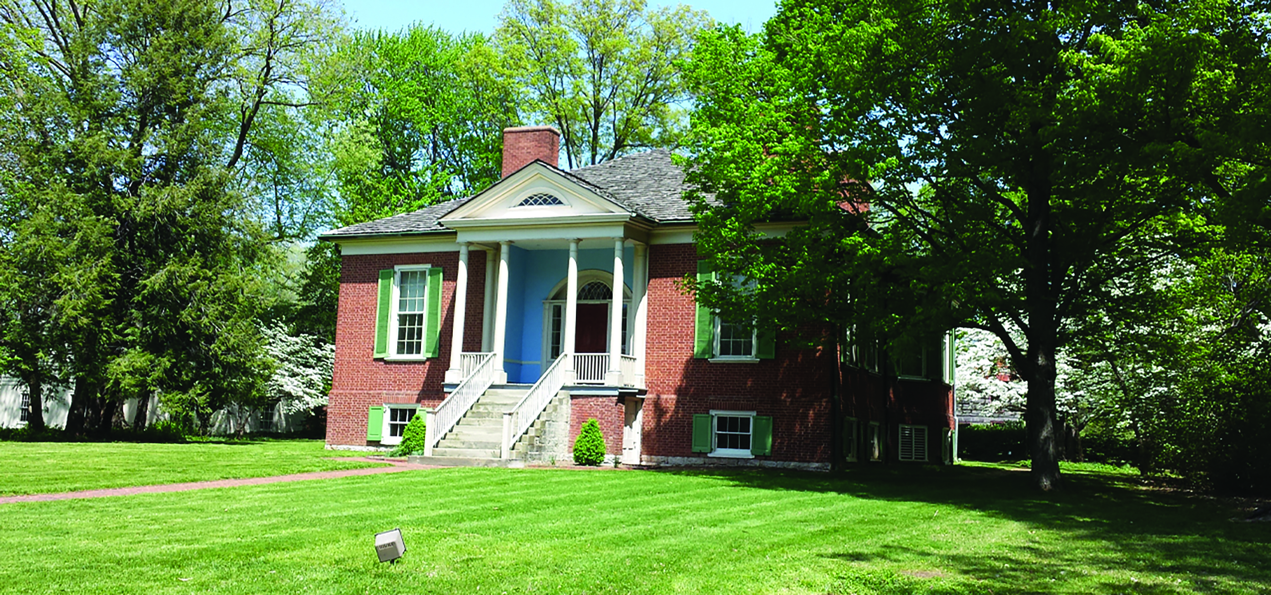 An image of a red brick home nestled among the trees.