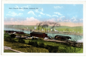 Color postcard of a steel making factory along the Ohio River. Fields and hills are visible in the foreground and background.